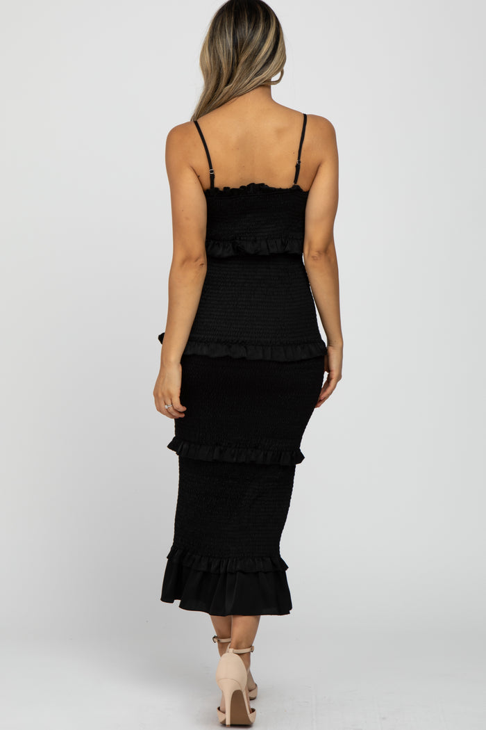 woman wearing a black ruffled midi dress with spaghetti straps and a fitted silhouette