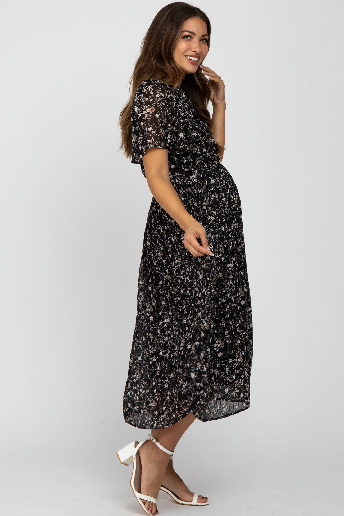 woman wearing a black floral maternity dress with short sleeves and a visible baby bump