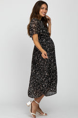 woman wearing a black floral maternity dress with short sleeves and a visible baby bump