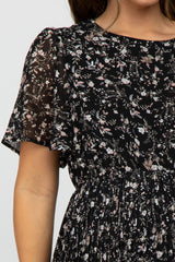 woman wearing a black floral print maternity dress with short flutter sleeves and a gathered waist