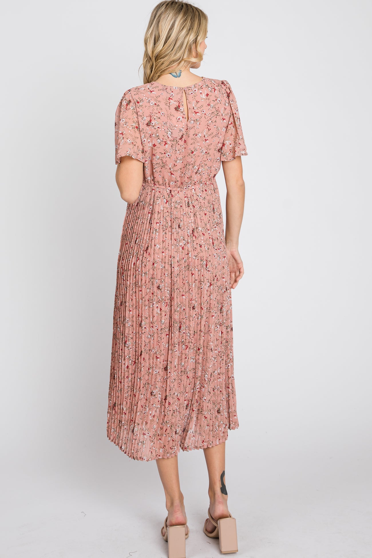 woman wearing a pink floral pleated midi dress with short sleeves, view from the back