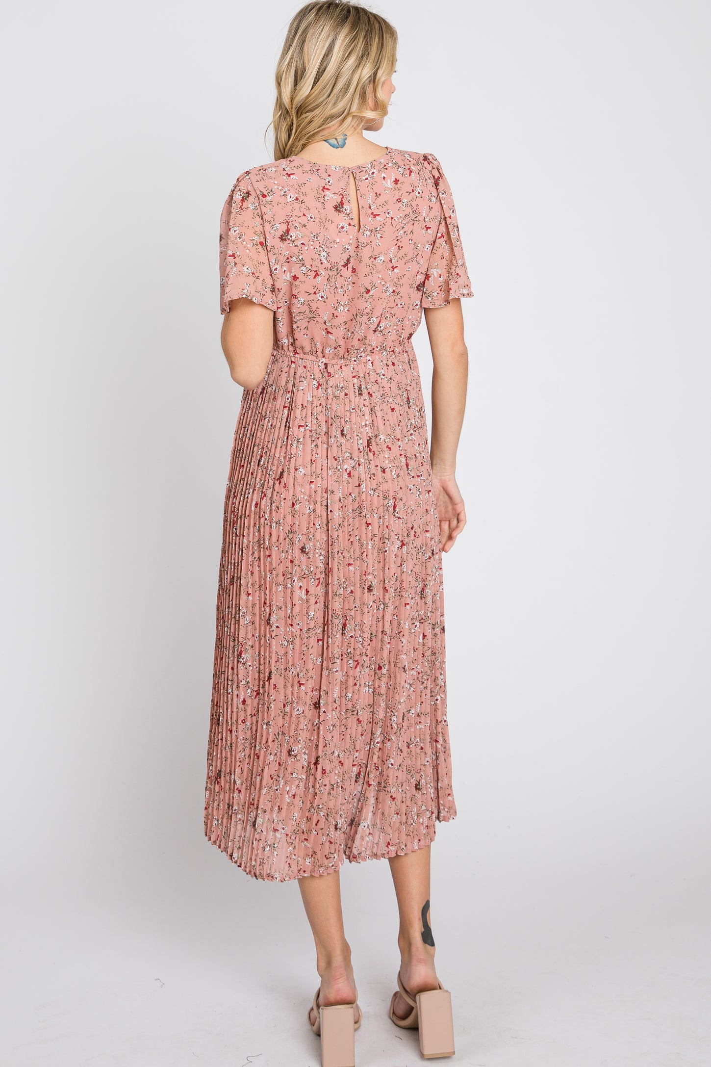 woman wearing a pink floral pleated midi dress with short sleeves, view from the back