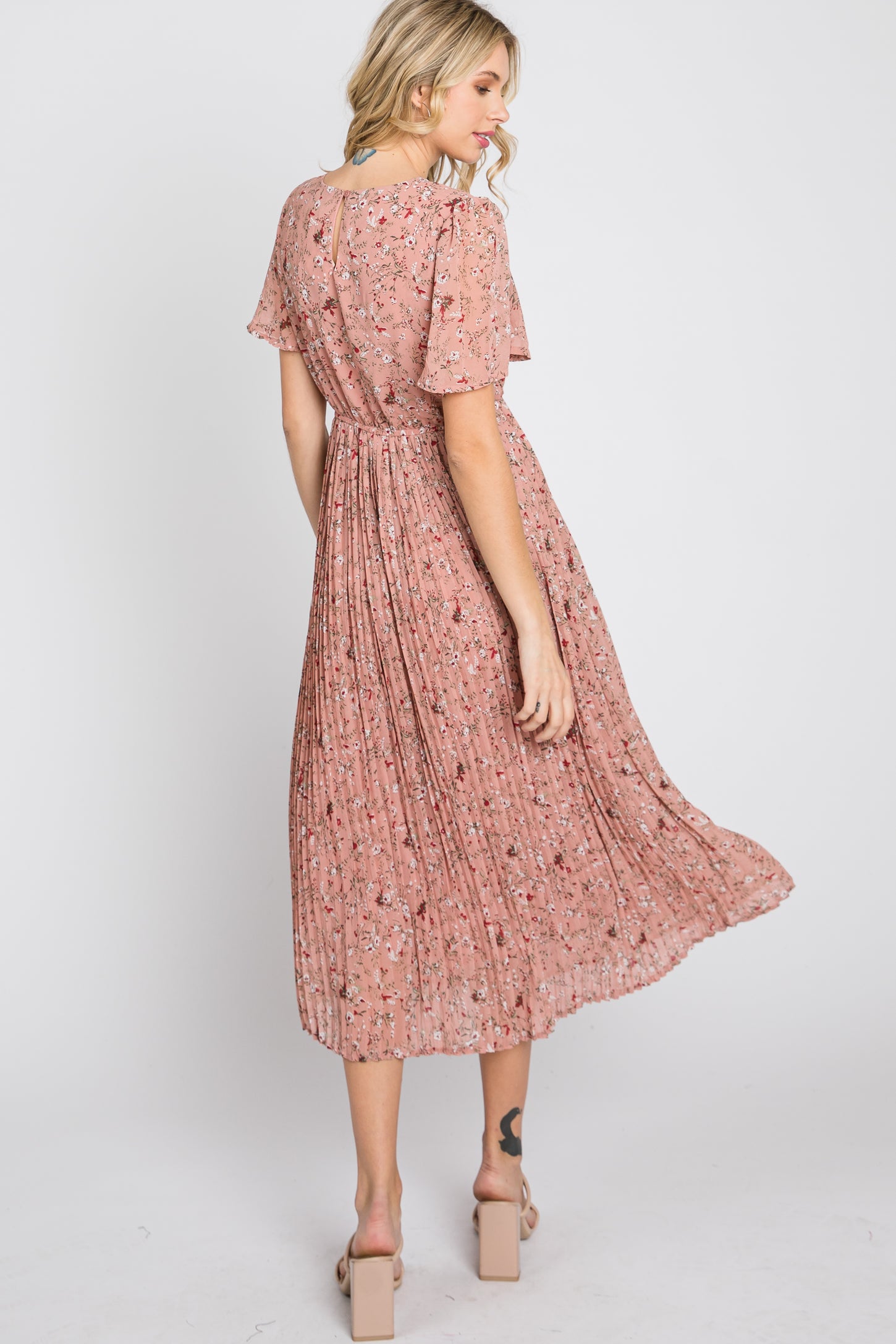 woman wearing a dusty rose floral pleated midi dress with short sleeves and tan block heels