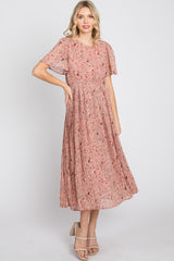 woman wearing a pink floral midi dress with flutter sleeves and a pleated skirt