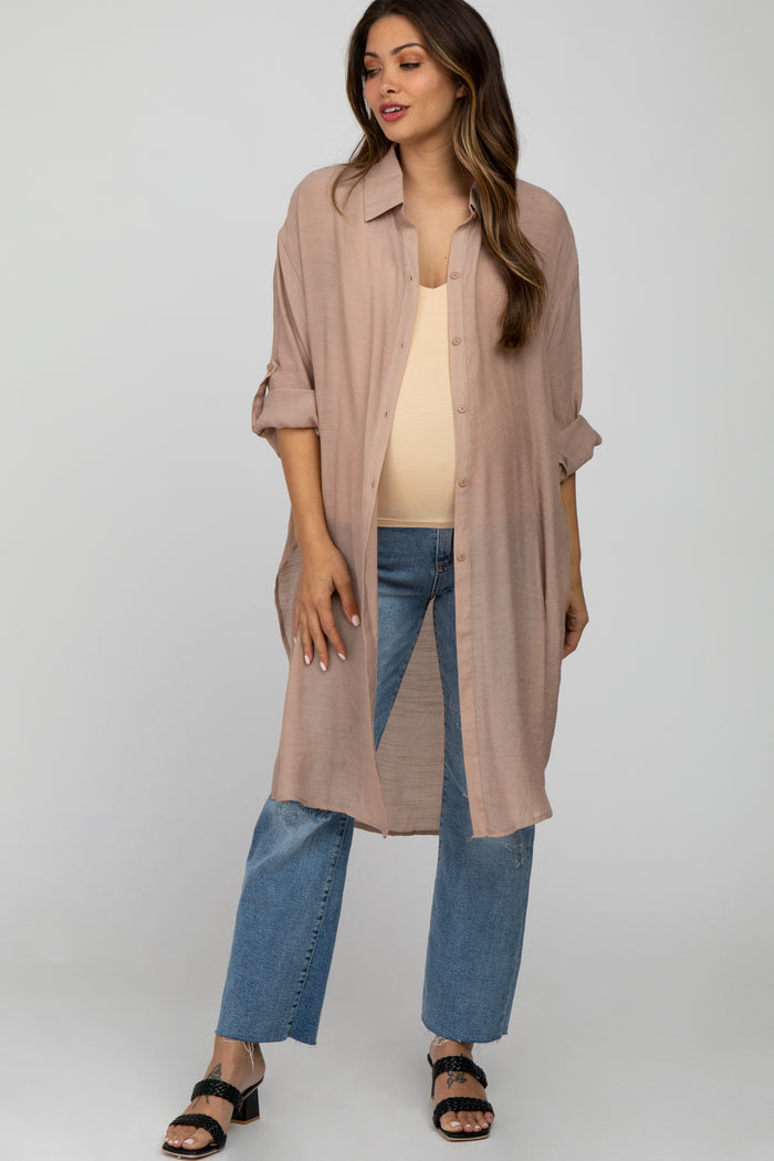 woman wearing a beige maternity shirt dress over a tank top, paired with light blue jeans, showcasing her baby bump