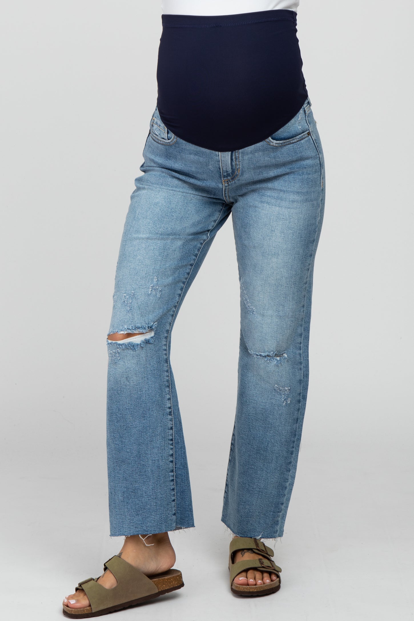 woman wearing blue distressed maternity jeans with a navy waistband and open-toe sandals