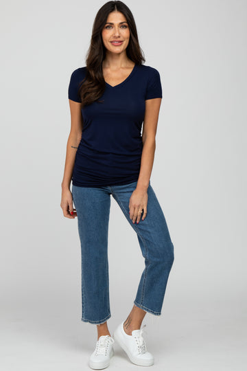 woman wearing a navy short sleeve v-neck top and light blue cropped jeans with white sneakers