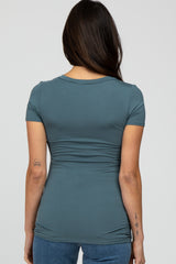 woman wearing a teal short sleeve fitted top with ruching details at the sides and back
