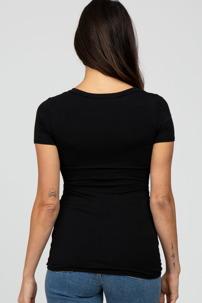 woman wearing a black short sleeve fitted top with gathered detailing at the waist