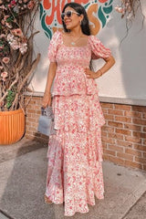 woman wearing a pink floral tiered maxi dress with puff sleeves and a square neckline, accessorized with sunglasses and a handbag
