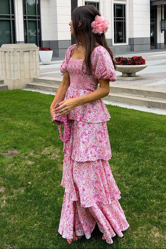 woman wearing a pink floral tiered maxi dress with puff sleeves and a flower in her hair