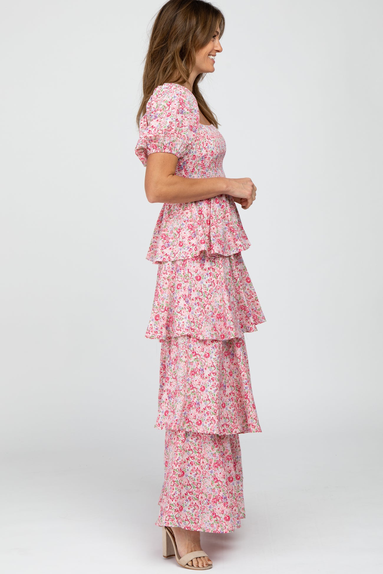 woman wearing a pink floral tiered maxi dress with puff sleeves and a side profile view