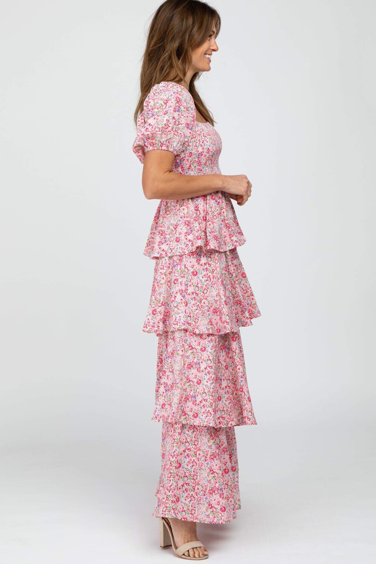 woman wearing a pink floral tiered maxi dress with puff sleeves and a side profile view