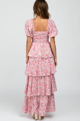 Back view of a woman wearing a pink floral tiered maxi dress with puff sleeves and a smocked bodice