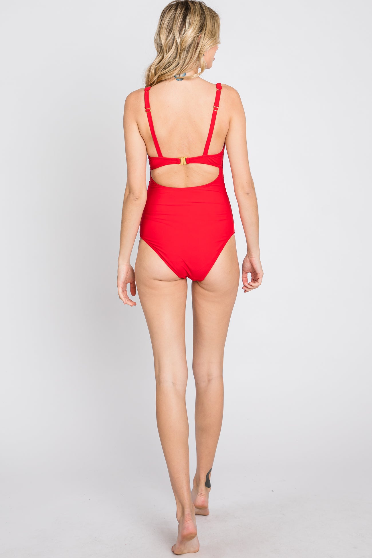 woman wearing a red one-piece swimsuit with a back cutout and adjustable straps, seen from behind