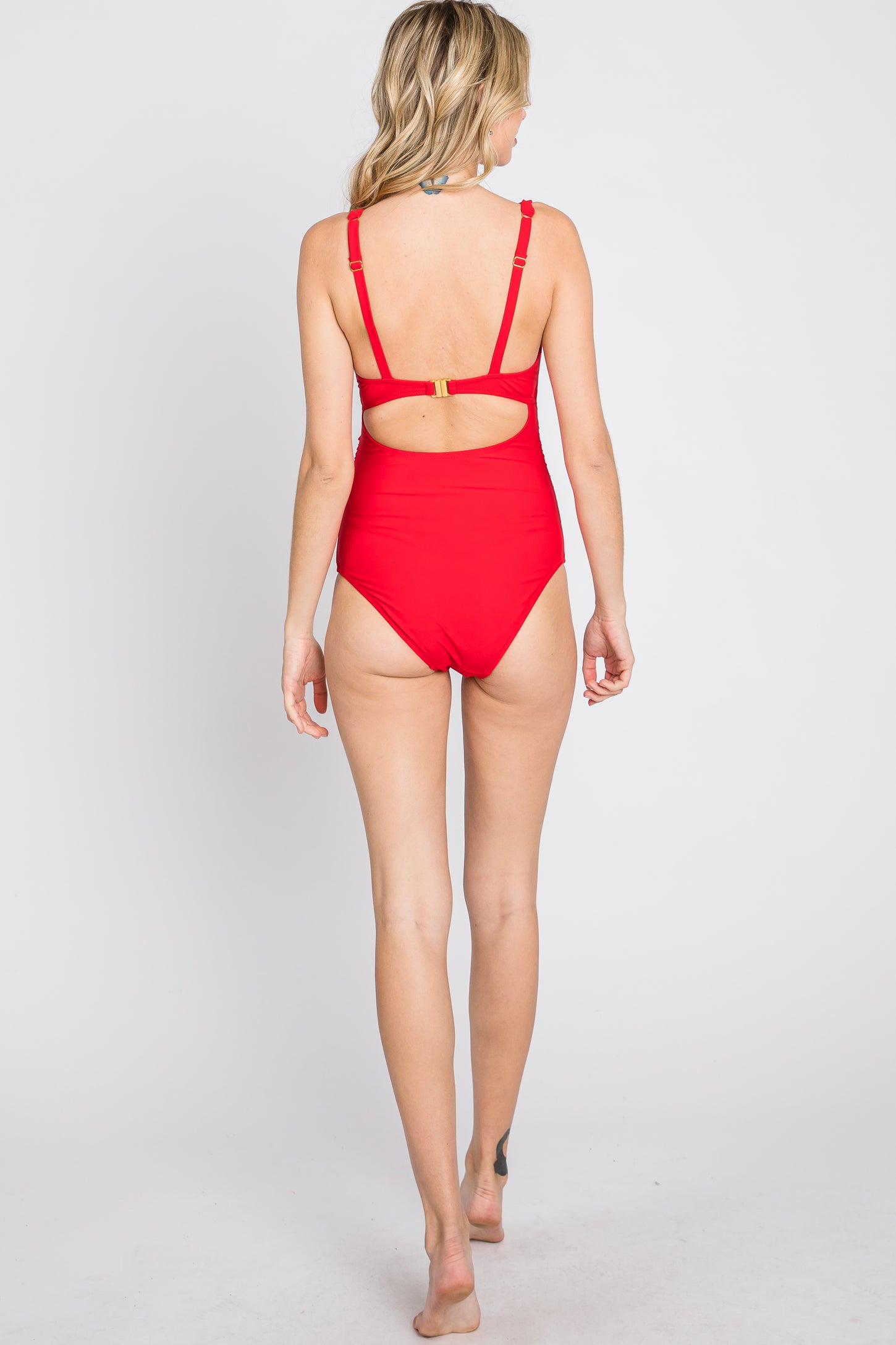 woman wearing a red one-piece swimsuit with a back cutout and adjustable straps, seen from behind