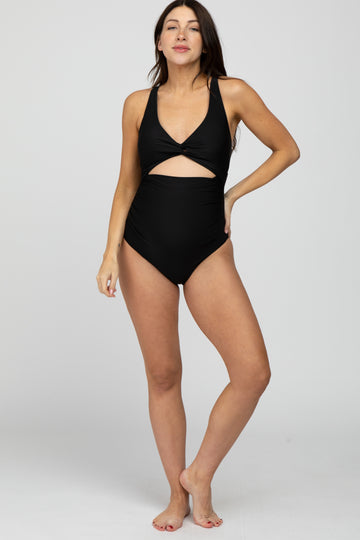 pregnant woman wearing a black one-piece maternity swimsuit with a front cutout and twist detail