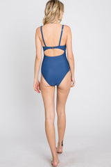 woman wearing a blue one-piece swimsuit with a cutout back design
