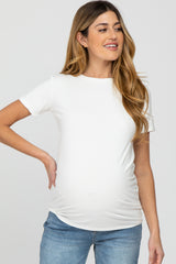 woman wearing a white short sleeve maternity top with a visible baby bump and styled with light blue jeans