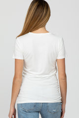 woman wearing a white short sleeve maternity top, viewed from the back, paired with blue denim jeans