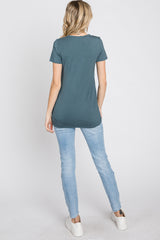woman wearing a dark teal short sleeve top and light blue skinny jeans, viewed from the back