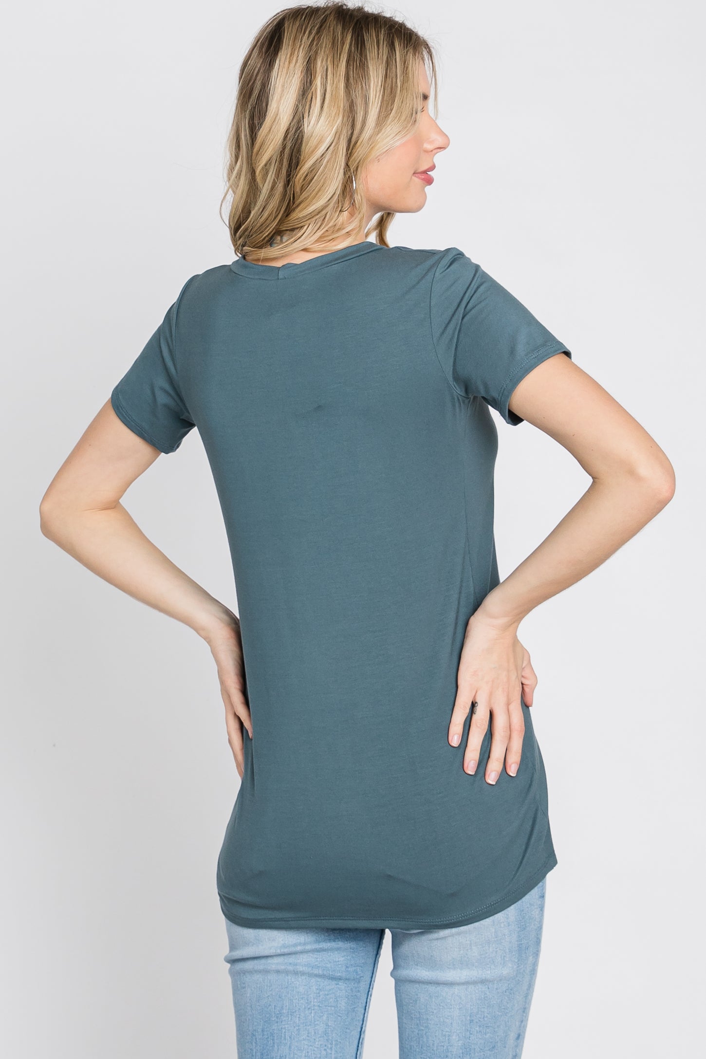woman wearing a teal short sleeve t-shirt paired with light blue jeans, seen from the back
