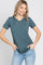 woman wearing a teal short sleeve top with a round neckline and light blue jeans