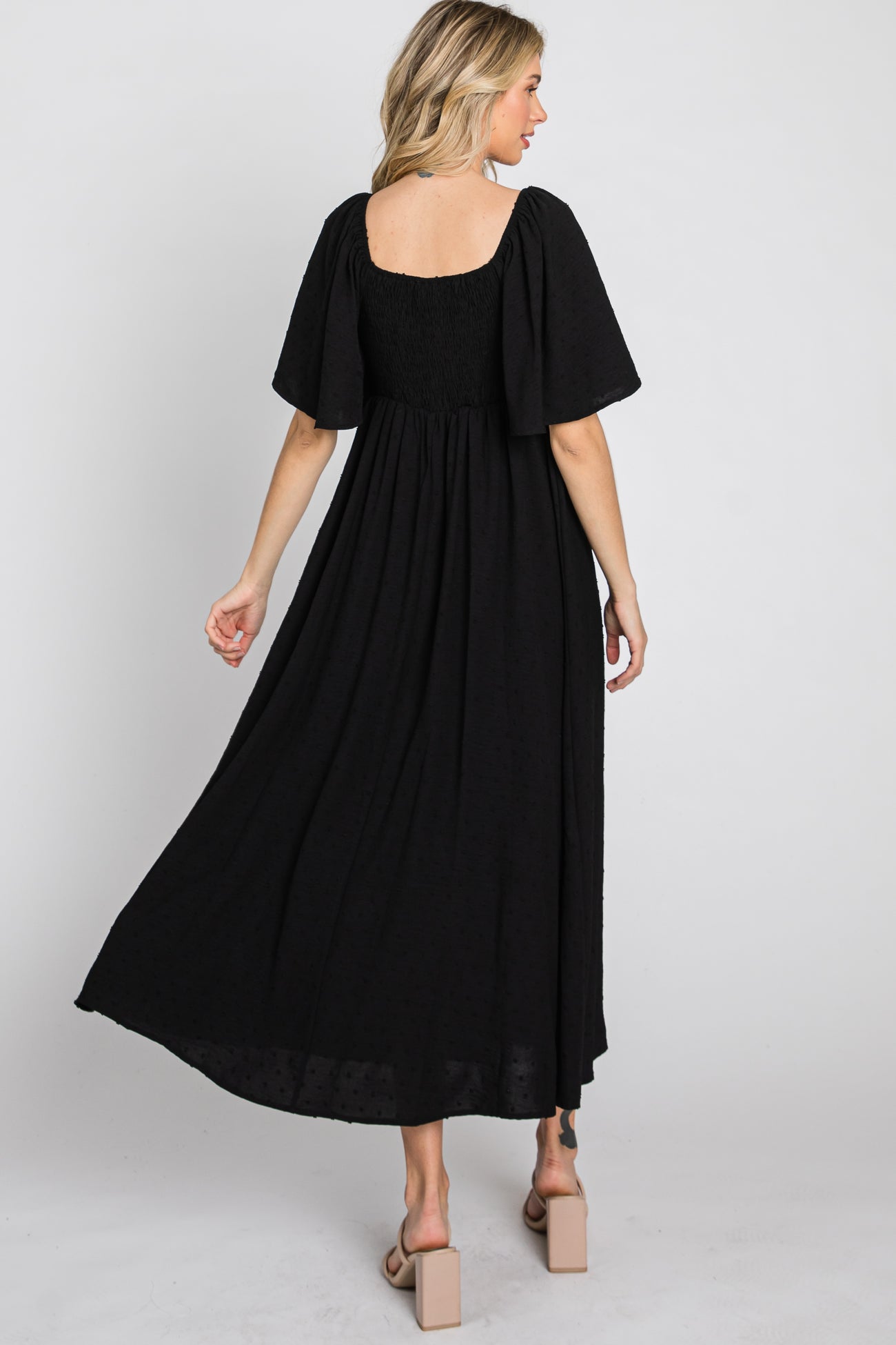 woman wearing a black long maxi dress with short flutter sleeves and a smocked back