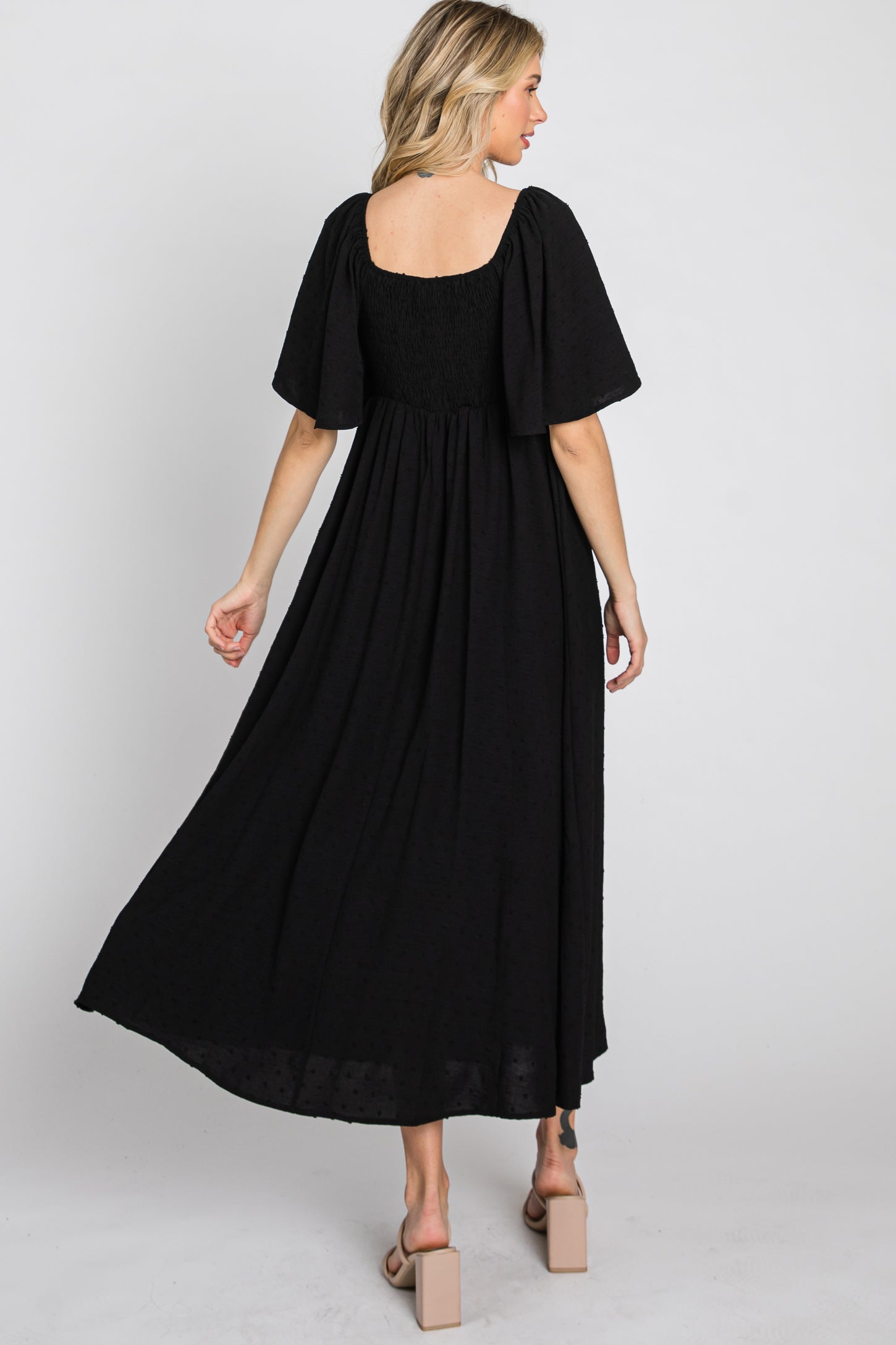 woman wearing a black long maxi dress with short flutter sleeves and a smocked back