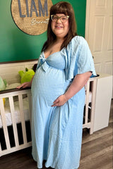 woman wearing a light blue maternity dress with short sleeves and a tie front, showcasing her baby bump
