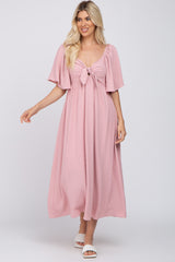 woman wearing a light pink maxi dress with flutter sleeves and a tie-front detail