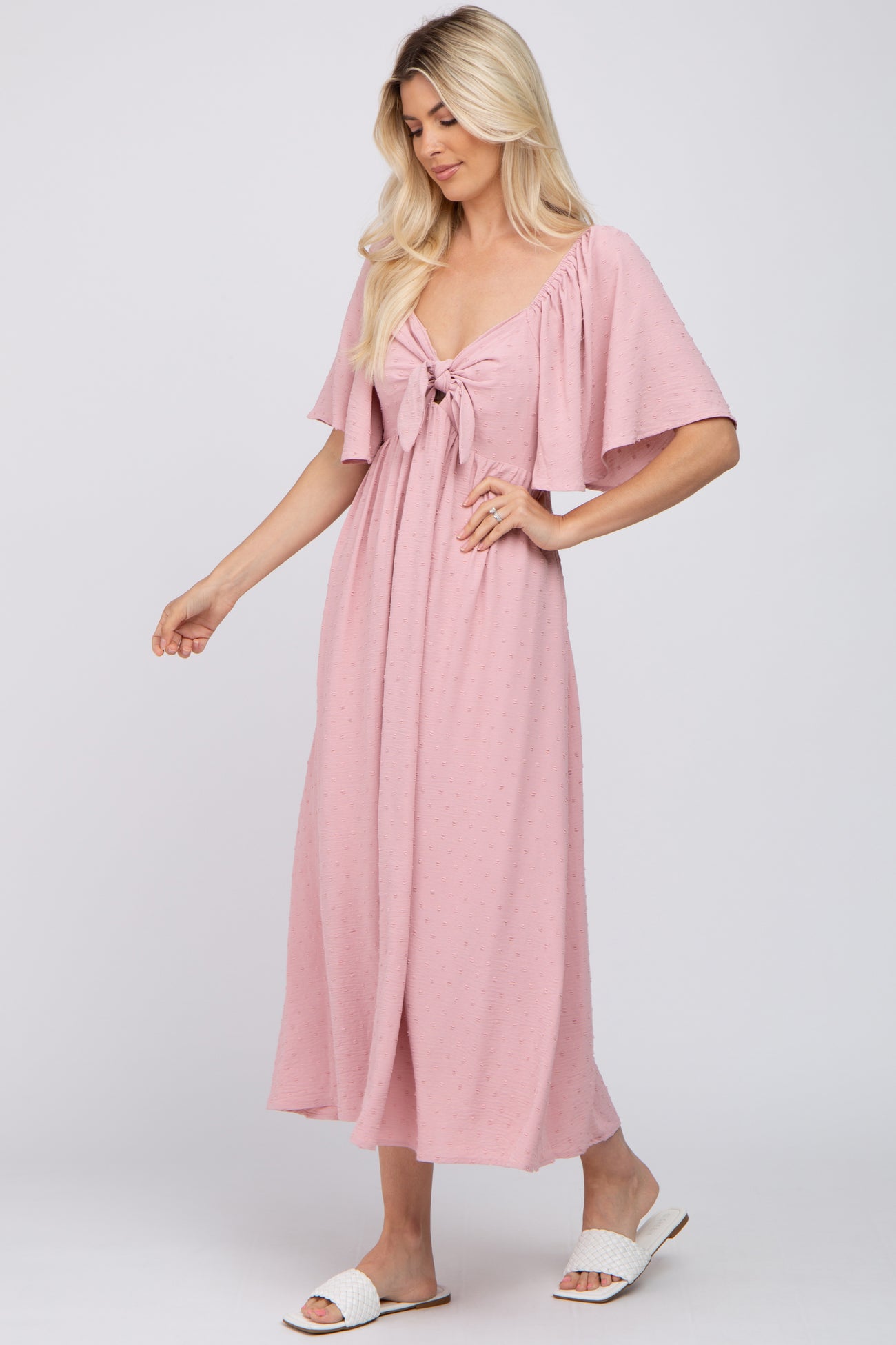 woman wearing a pink maxi dress with flutter sleeves and a front tie detail