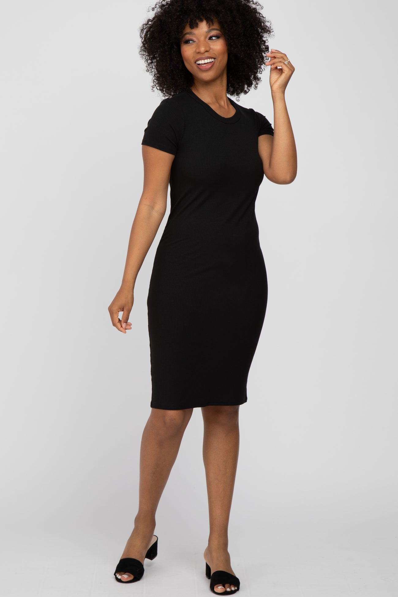woman wearing a black short sleeve ribbed bodycon dress and black slip-on shoes