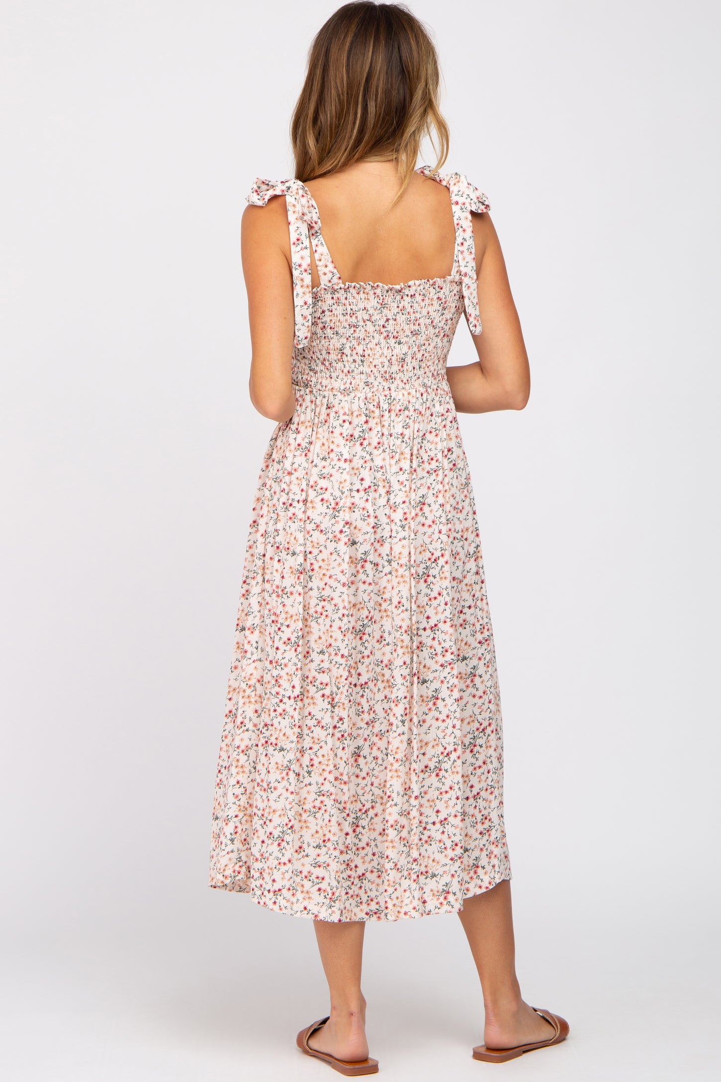 woman wearing a pink floral maxi dress with smocked bodice and tie shoulder straps, seen from the back