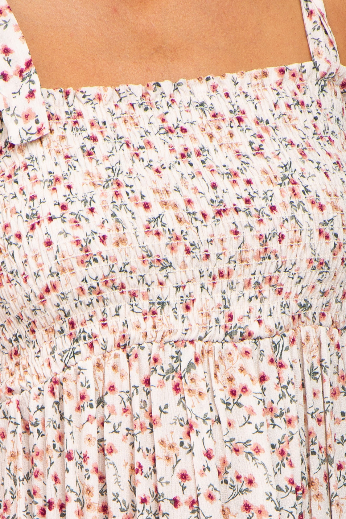 close-up of a smocked floral print dress in soft pastel colors with thin shoulder straps