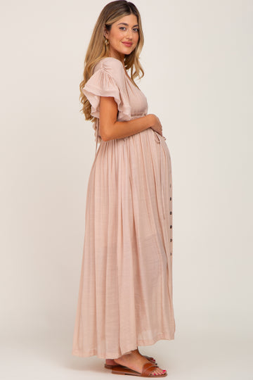 woman wearing a light pink maternity maxi dress with ruffle sleeves and a visible baby bump