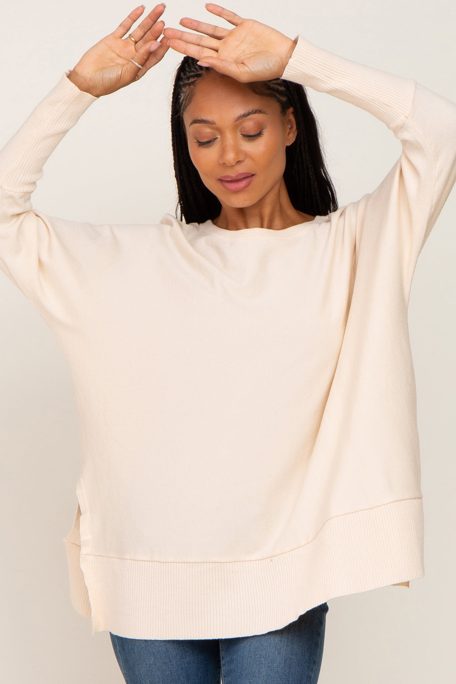woman wearing cream oversized knit sweater and blue jeans