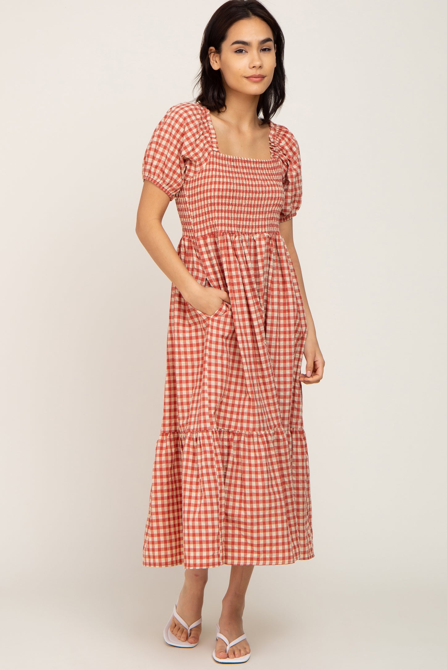 woman wearing a red and white gingham puff sleeve maxi dress with a square neckline and pockets