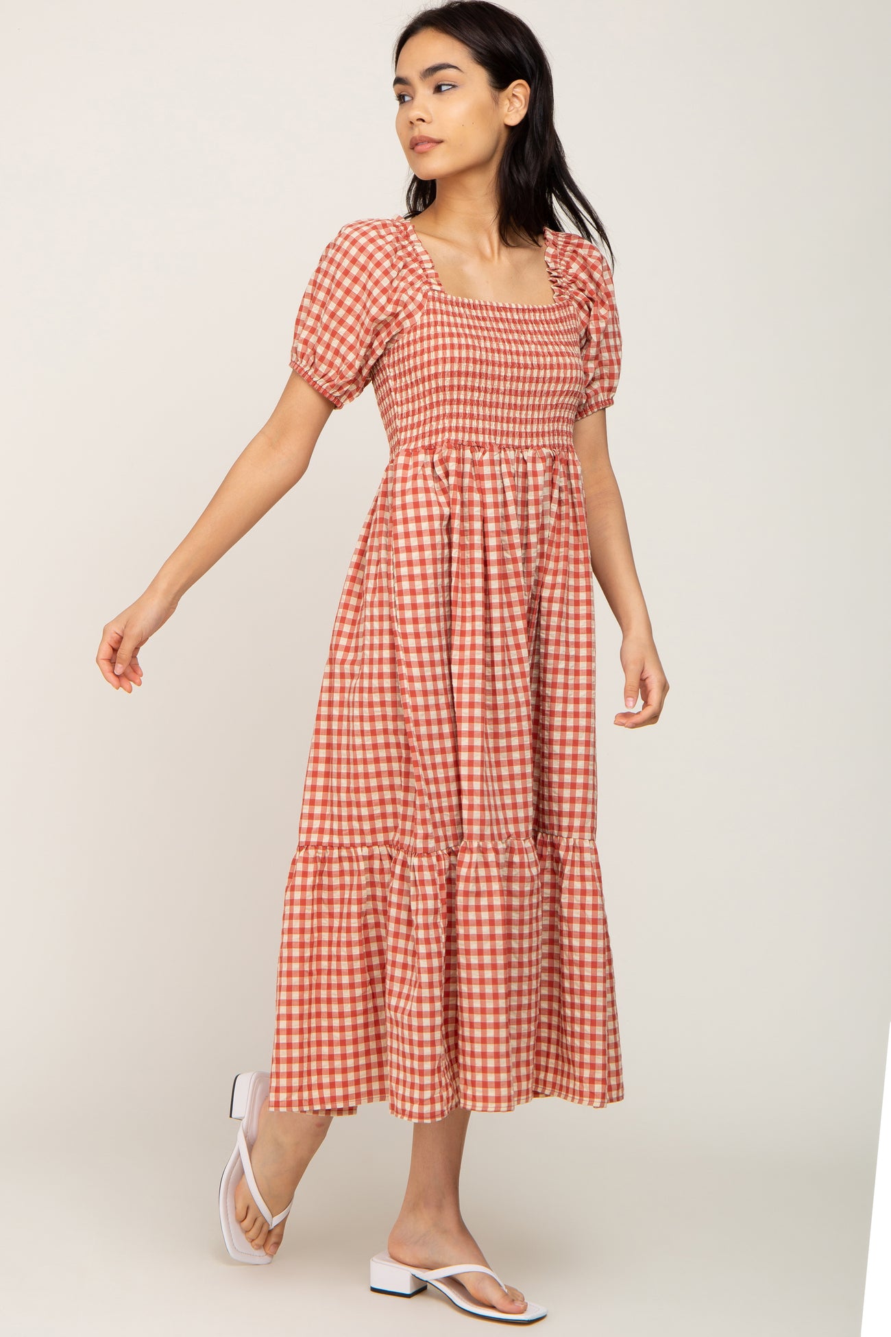 woman wearing a red and white gingham midi dress with puff sleeves and a tiered skirt