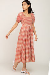 woman wearing a red and white gingham midi dress with puff sleeves and a tiered skirt
