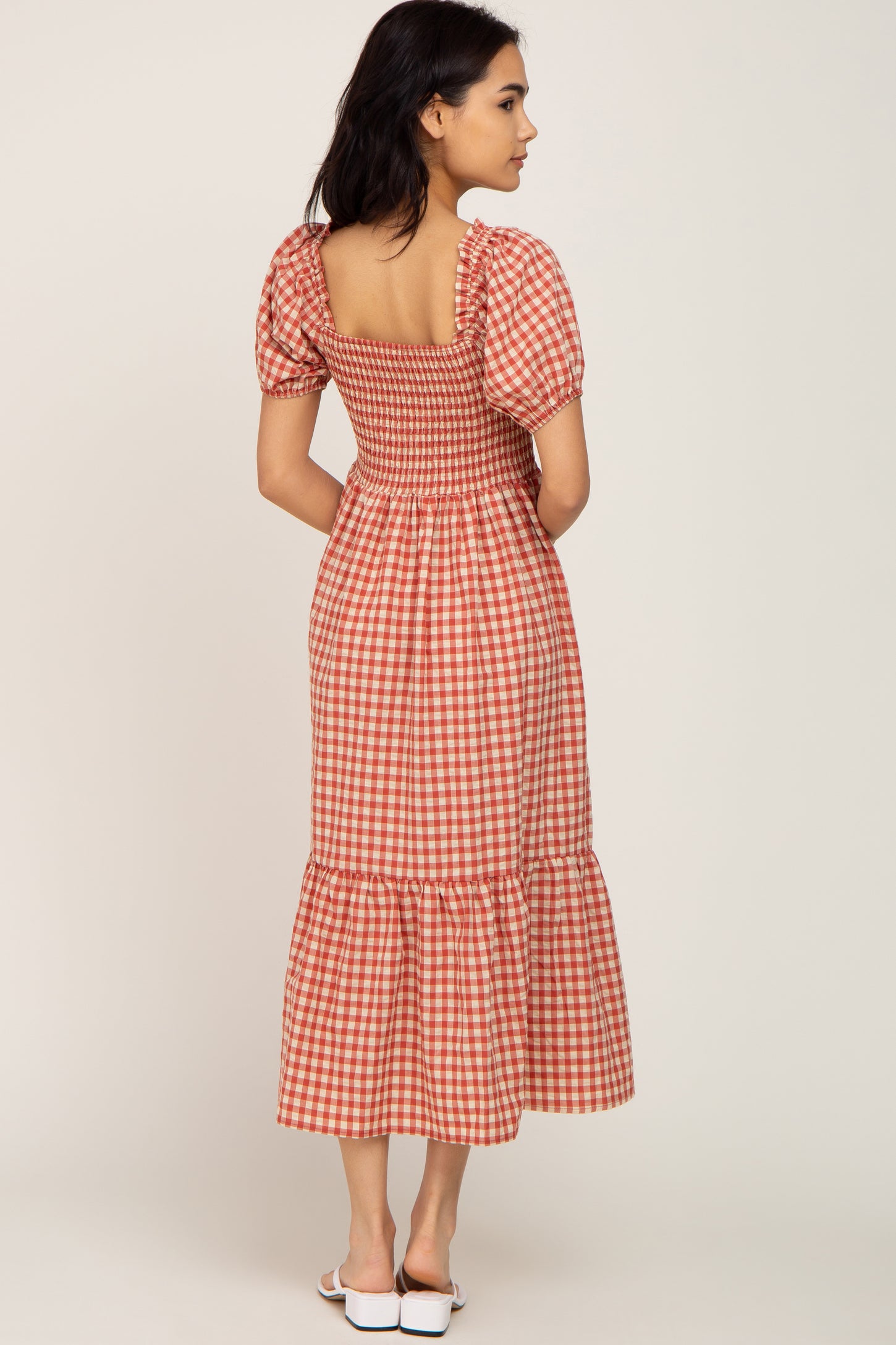 woman wearing a red and white gingham midi dress with a smocked bodice and puff sleeves, viewed from the back