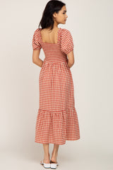 woman wearing a red and white gingham midi dress with a smocked bodice and puff sleeves, viewed from the back