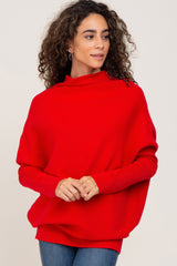woman wearing a red oversized knit sweater with a high neckline and relaxed fit, styled with denim jeans