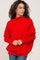 woman wearing a red oversized knit sweater with a high neckline and relaxed fit, styled with denim jeans