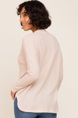 woman wearing a light pink long sleeve top with a textured pattern and a relaxed fit, turned slightly to the side