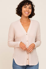 woman wearing a light pink cardigan with a v-neckline and button front, paired with blue jeans