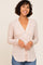 woman wearing a light pink cardigan with a v-neckline and button front, paired with blue jeans