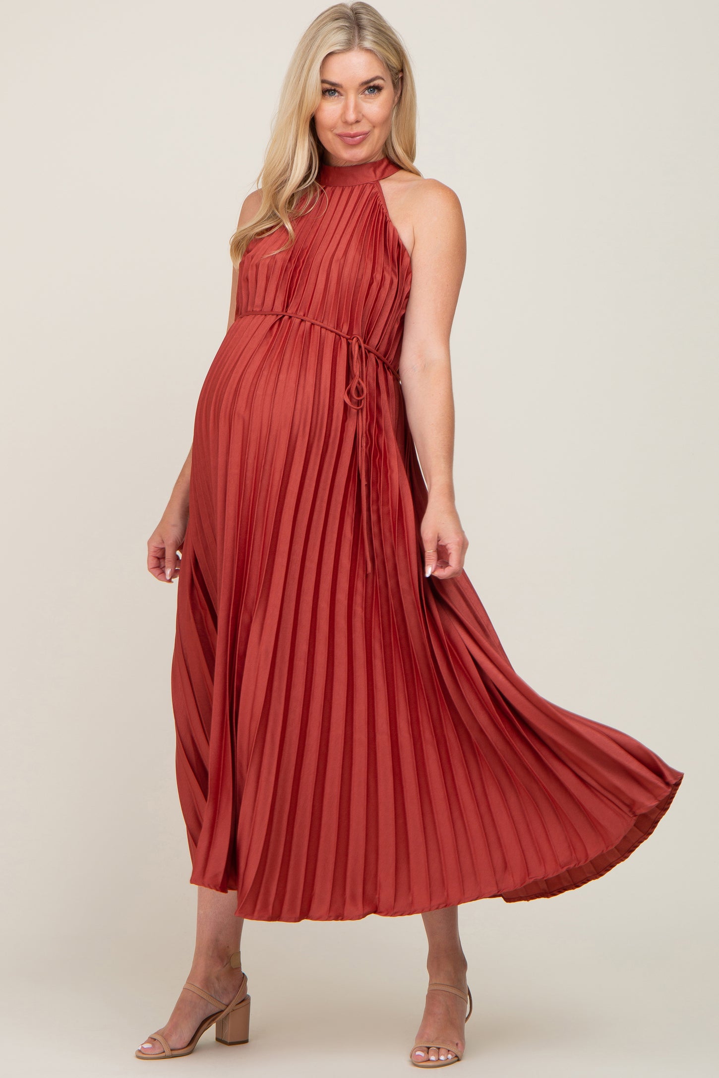 woman wearing a rust pleated maternity dress with a tie detail and a visible baby bump
