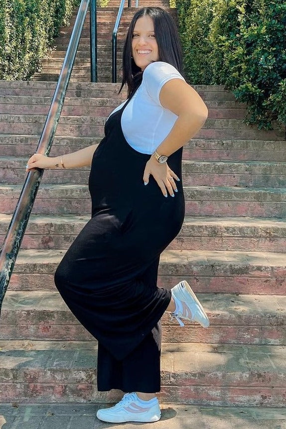 woman wearing a black maternity maxi dress over a white t-shirt, showing her baby bump while standing on outdoor steps