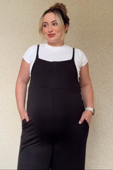 woman wearing a black maternity jumpsuit over a white t-shirt with pockets, showcasing her baby bump